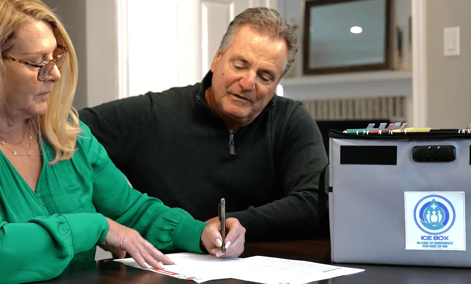 an older couple signing their insurance policy to be put in their ICE Box